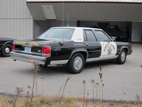 1991 Ford LTD Crown Victoria - This 1991 Ford Crown Victoria LTD police car is seen from the rear 3/4 angle, parked near an open garage.