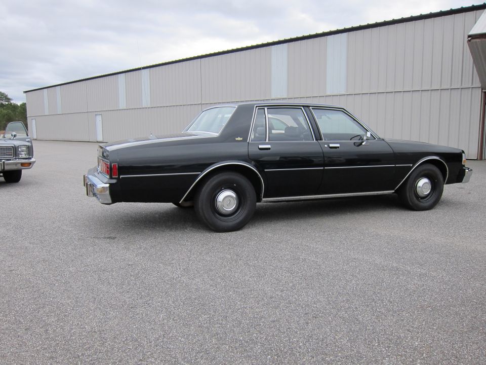 Black sedan parked next to a silver car in front of a large building