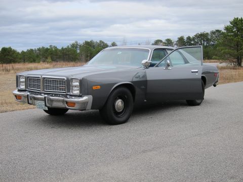 1991 Ford LTD Crown Victoria - This gray sedan, possibly a Dodge, is parked on an asphalt road with trees in the background and the driver's door ajar.