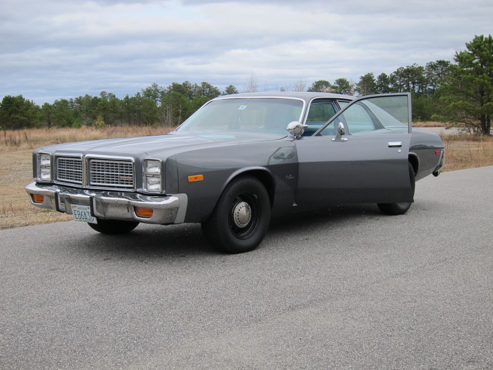 Gray sedan with driver's door open, showing a black steel wheel and chrome bumper