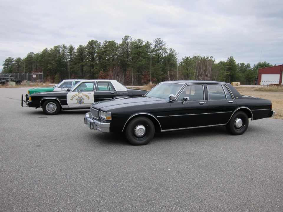 Black unmarked sedan and a Highway Patrol car parked side-by-side