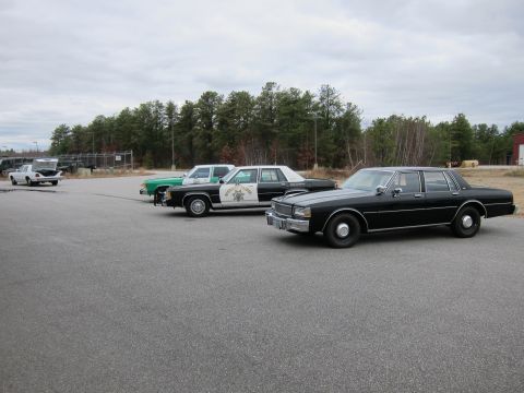 1991 Ford LTD Crown Victoria - Several police cars and a white pickup truck are parked in an asphalt lot.