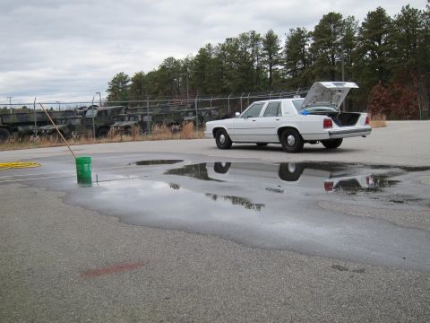 1991 Ford LTD Crown Victoria - A white 1991 Ford Crown Victoria LTD sedan is parked with its trunk open, reflecting in puddles on the asphalt.