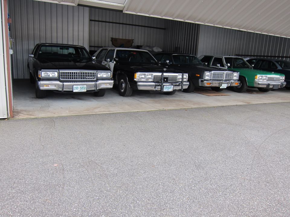 Row of sedans parked in a garage, including a black 1991 Ford Crown Victoria LTD