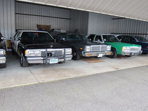 1991 Ford LTD Crown Victoria - Several police cars and other vehicles are parked in a covered bay.