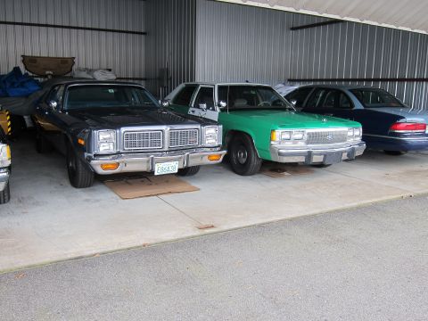 1991 Ford LTD Crown Victoria - A green 1991 Ford Crown Victoria is parked in a garage next to other vehicles. The front grille and Ford badge are clearly visible.