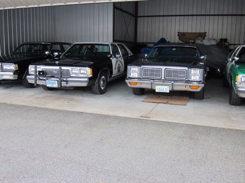 1991 Ford LTD Crown Victoria - Several police cars are parked inside a garage, including a 1991 Ford Crown Victoria LTD.