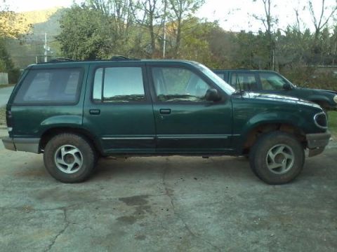 1993 Ford F-150 - A green SUV is parked on a concrete surface with another vehicle behind it.