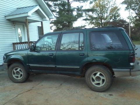 1993 Ford F-150 - Green 1995 Ford Explorer parked next to a house.