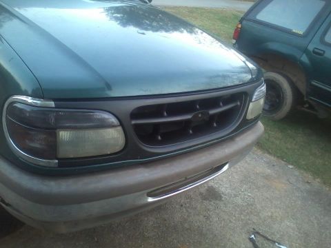 1993 Ford F-150 - Front view of a green SUV, showing its grille and headlights, with another vehicle in the background.