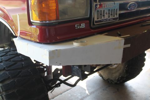 1990 Ford Bronco - A cardboard mockup is taped to the front bumper of a red 1990 Ford Bronco, showing a custom bumper modification.