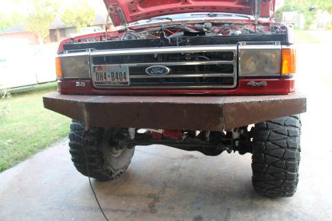 1990 Ford Bronco - A red Ford truck from the front, a custom metal bumper and a 4x4 badge on the fender.