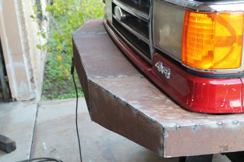 1990 Ford Bronco - A custom-fabricated metal bumper is installed on the front of a red truck, showing the 4x4 emblem.