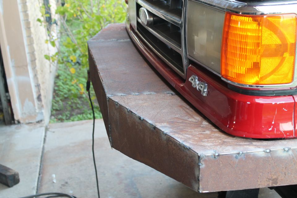 Custom metal bumper welded onto the front of a red truck with a 4x4 badge visible