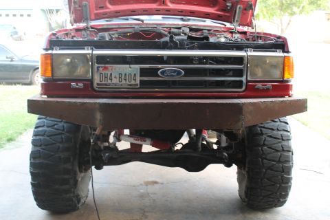 1990 Ford Bronco - A red Ford truck from the early 1990s is shown from the front with its hood open and a custom bumper installed.