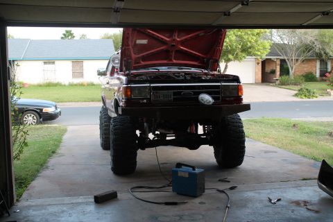 1990 Ford Bronco - This lifted Ford truck, likely from the late 1980s, is undergoing some work in a residential garage.
