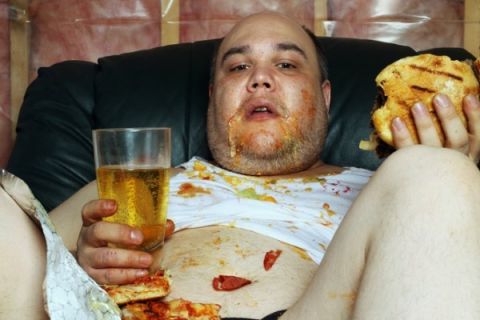1989 Ford Bronco - A man sits on a couch, covered in food stains, holding a burger and a glass of beer.