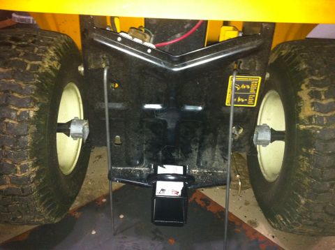 2007 Subaru Impreza - The rear hitch assembly of a yellow lawn tractor is shown, its large tires and a tow hitch.