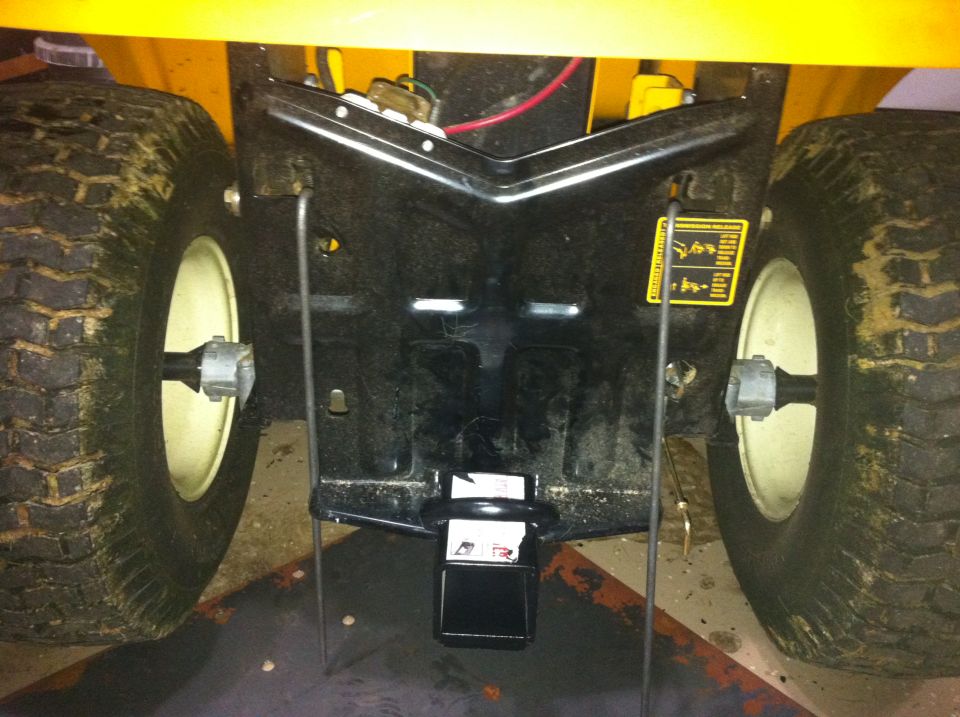 Rear hitch assembly of a yellow lawn tractor with large tires