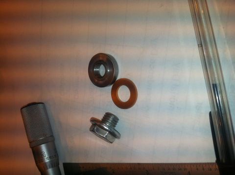 1992 Ford Bronco - A transmission pan drain plug, washer, and a micrometer are laid out on a surface, with a ruler visible at the bottom.