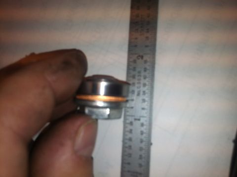 1992 Ford Bronco - A drain plug with a copper washer is shown next to a ruler for size comparison.