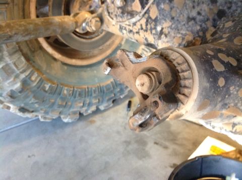 1966 Ford Bronco - A close-up view shows a damaged U-joint on a vehicle's rear axle, covered in mud.