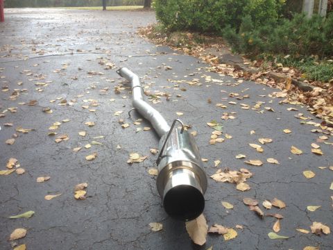 1996 Ford Bronco - An aftermarket exhaust pipe rests on a leaf-strewn driveway, suggesting a recent installation or removal.