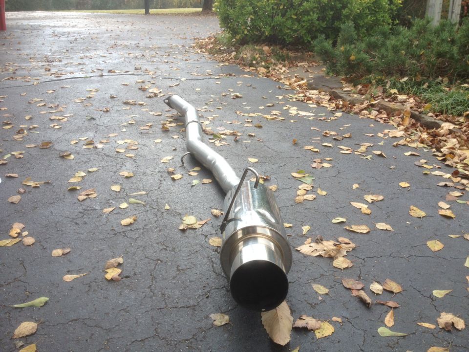 Exhaust pipe lying on asphalt covered with fallen leaves