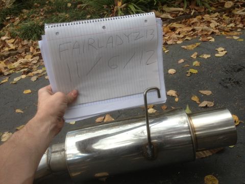 1996 Ford Bronco - Notebook with writing and a chrome exhaust muffler are shown outdoors on a paved surface with fallen leaves.
