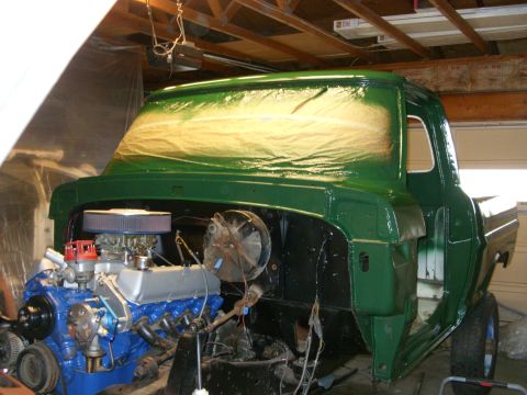 1967 Ford F-250 - A green Ford truck is undergoing restoration in a garage, with its engine exposed and the cab area covered for painting.