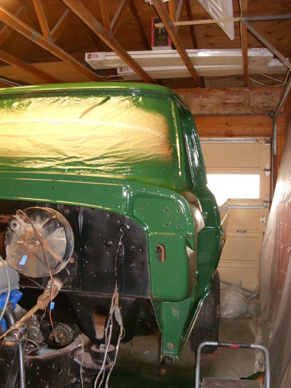 Green 1967 Ford F-250 cab, partially painted, in a garage