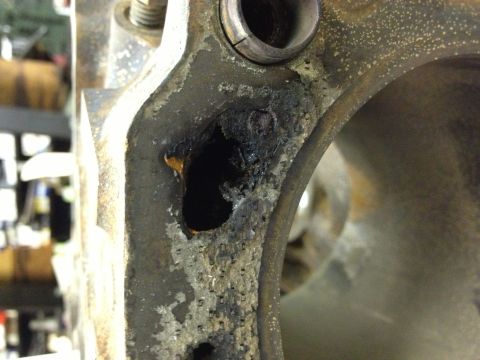 1987 Ford Ranger - A damaged engine component displays significant corrosion and a hole, indicating wear and tear.