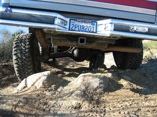 Underside rear view of Ford truck straddling rock, plate 2PUB201, mud tires