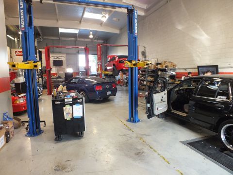2003 Ford Crown Victoria - Performance shop bay: blue Rotary lifts, tool chest, red coupe lifted and a black sedan under service