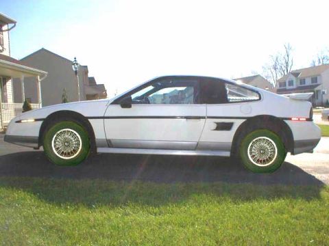 1994 Ford Crown Victoria - Side profile of a white Pontiac Fiero with wire wheels and green tires.