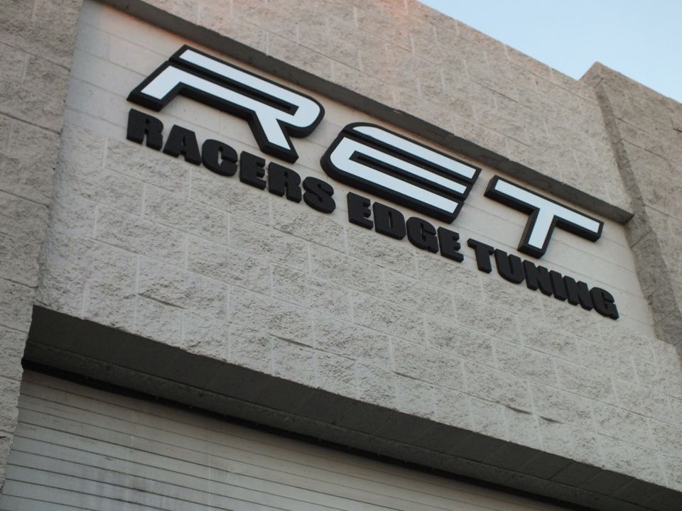 Racers Edge Tuning RET exterior building sign in black lettering on textured block wall