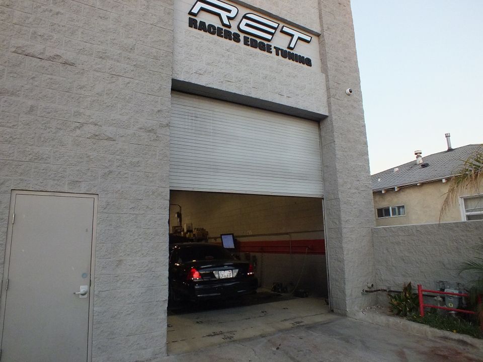 Racers Edge Tuning storefront with raised roll-up door and black sedan inside service bay