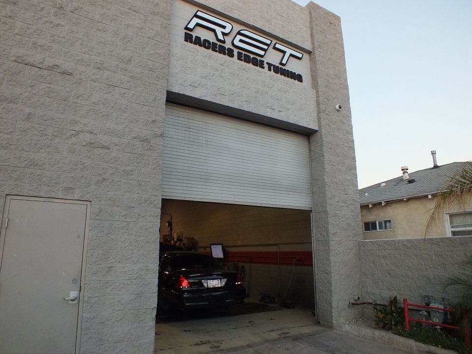 Racers Edge Tuning building front with garage door partly open and dark sedan in bay
