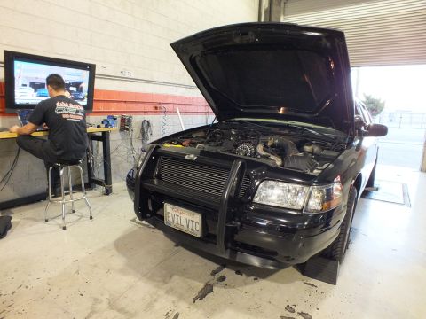 2003 Ford Crown Victoria - Wide-angle of a black sedan, hood open over an intercooler, tech logging data at the bench.