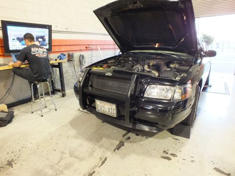 2003 Ford Crown Victoria - Front three-quarter of a black sedan with intercooler, EVIL VIC plate, tech tuning at the bench.