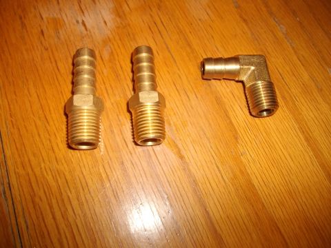1989 Ford Probe - Brass hose barb fittings, including two straight and one elbow piece, are laid out on a wooden surface.