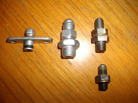1989 Ford Probe - Several metal automotive fittings and bolts are laid out on a wooden surface.