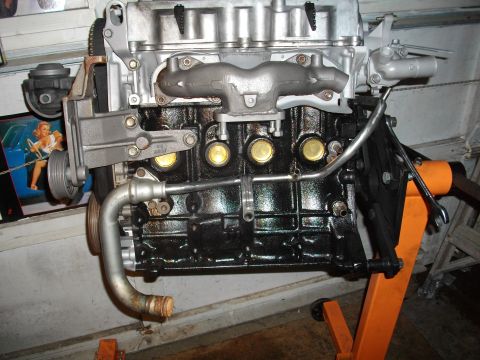 1989 Ford Probe - Engine assembly mounted on an orange engine stand, with a vintage pin-up poster visible behind it.