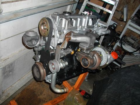1989 Ford Probe - A disassembled engine with a turbocharger is shown on an engine stand in a garage.