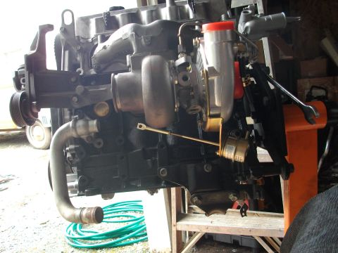 1989 Ford Probe - A turbocharged engine assembly is shown, with various components attached and a green hose coiled nearby.