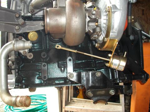 1989 Ford Probe - Close-up view of a turbocharger and wastegate actuator assembly attached to an engine block.