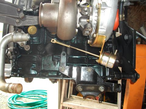 1989 Ford Probe - Turbocharger assembly attached to an engine block, with a green garden hose in the foreground.