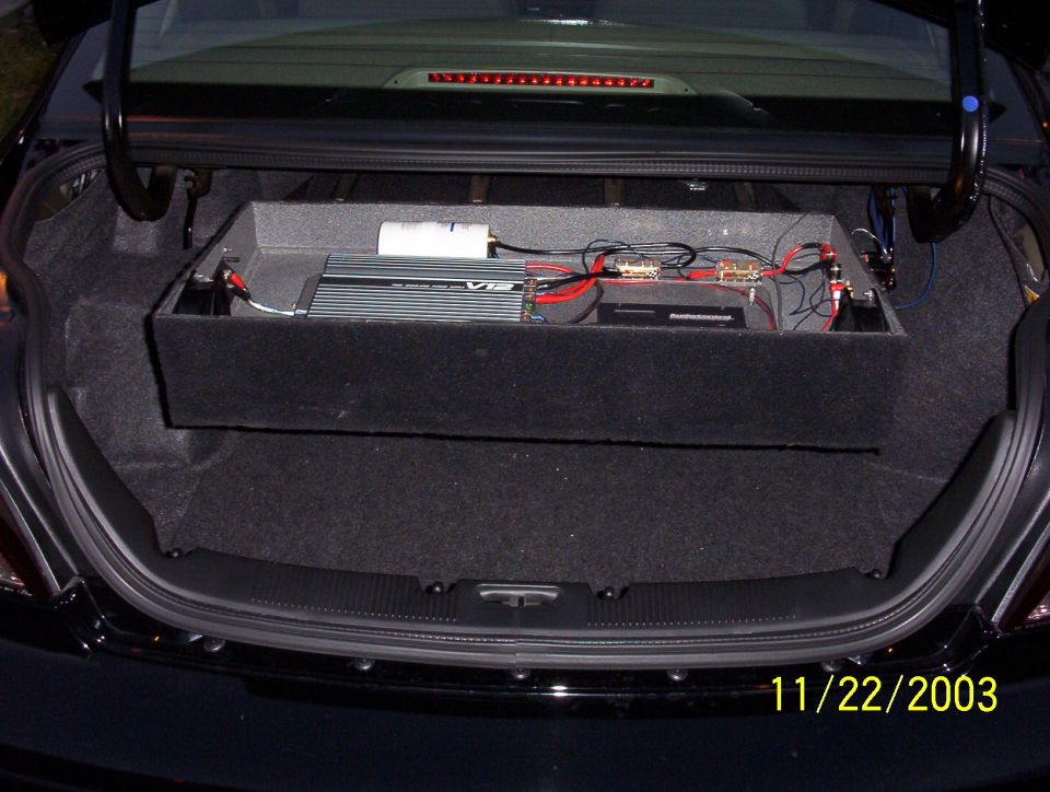 Car trunk interior with custom audio amplifier and subwoofer box installed. Date stamp shows 11/22/2003
