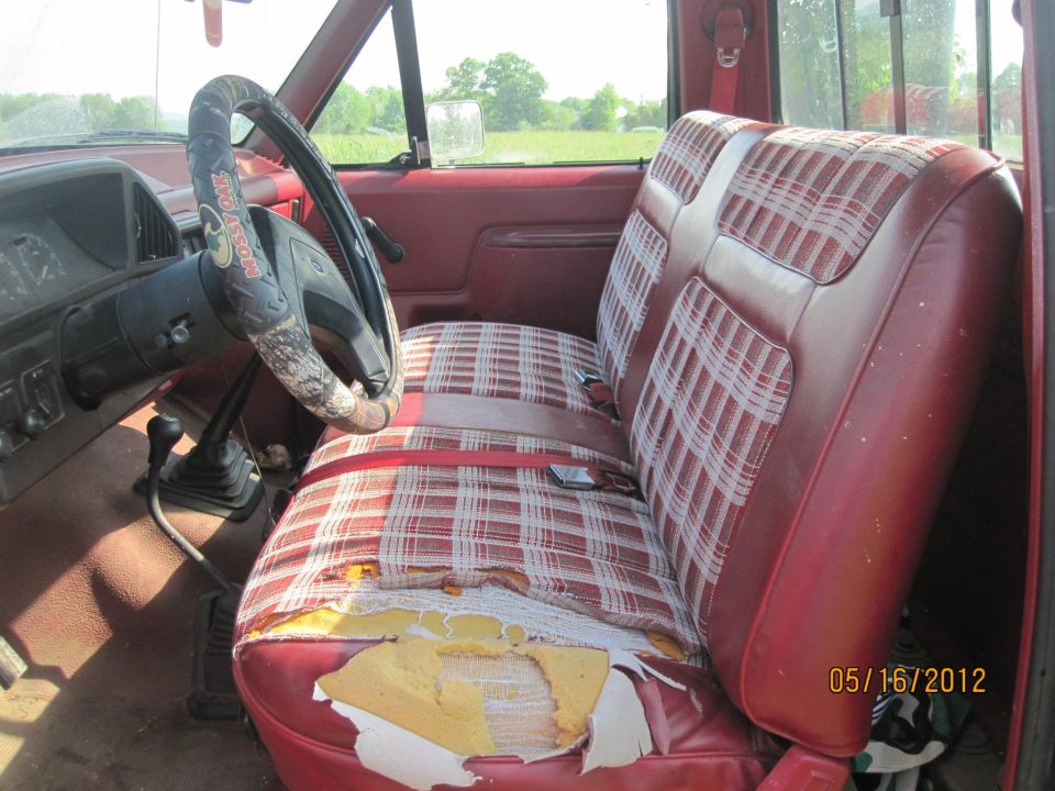 Interior of a 1988 Ford F-150 with red vinyl and plaid cloth seats, showing wear