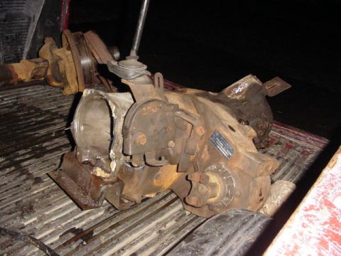 1992 Ford Bronco - A rusty removed transmission and transfer case assembly lying in a ribbed pickup bed at night, still joined to a driveshaft yoke and slip j…